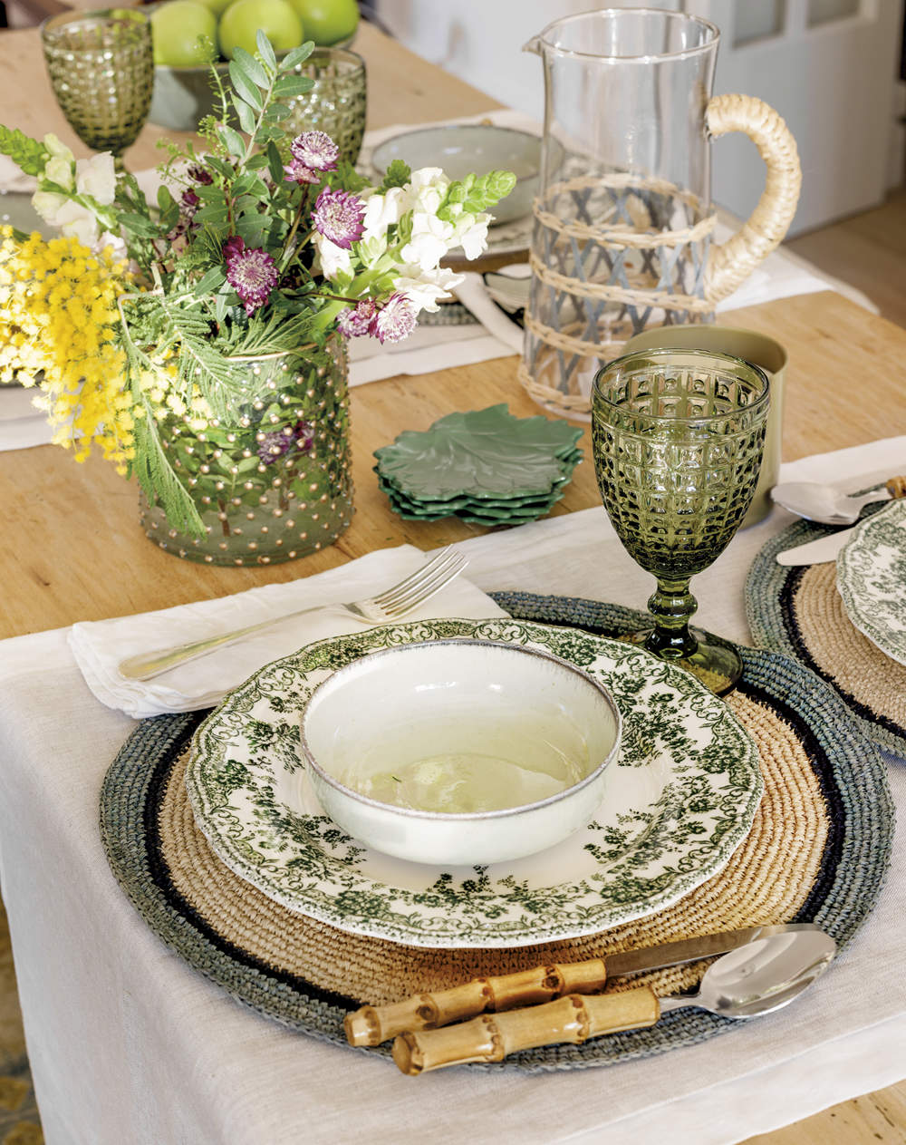 Vajilla verde de cerámica con flores y mantel individual blanco de lino, copa de cristal verde y jarra